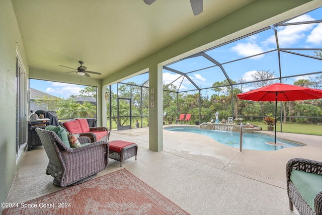 view of pool featuring pool water feature, a patio, glass enclosure, and ceiling fan