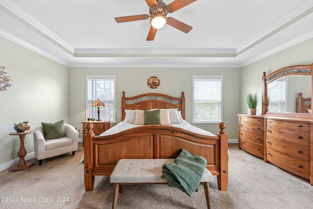 carpeted bedroom with ceiling fan, a raised ceiling, and crown molding