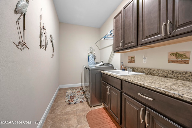 washroom with cabinets, light tile patterned floors, washer and clothes dryer, and sink