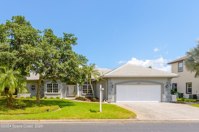 view of front of house with a garage, a front lawn, and central AC unit