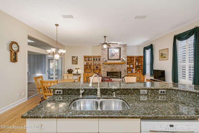 kitchen with sink, dark stone counters, white cabinetry, a fireplace, and light wood-type flooring