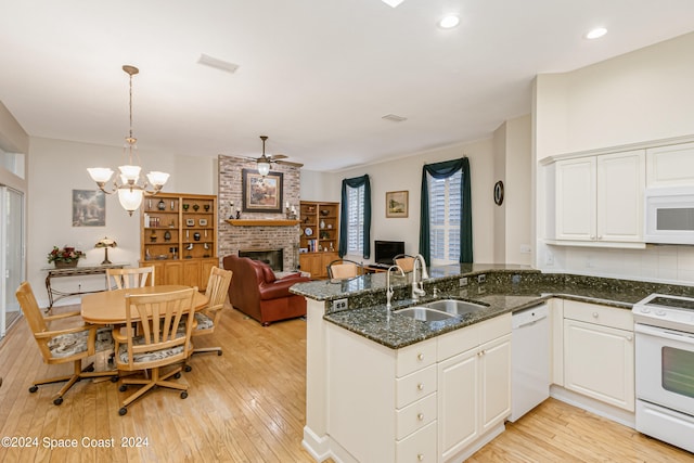 kitchen featuring a brick fireplace, decorative light fixtures, light hardwood / wood-style flooring, and white appliances