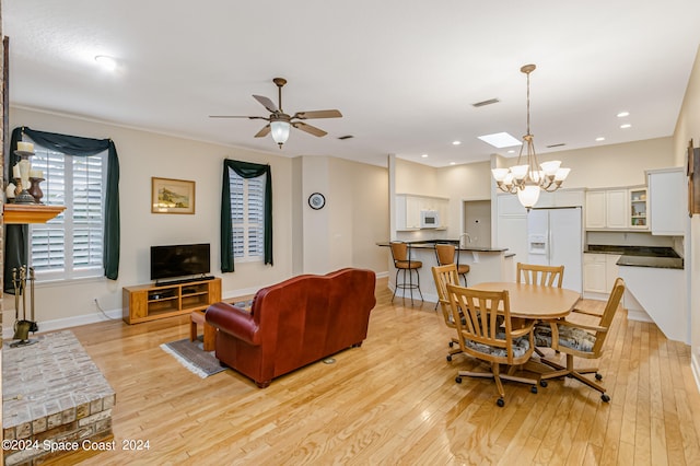 dining area featuring ceiling fan with notable chandelier, light wood-type flooring, and sink