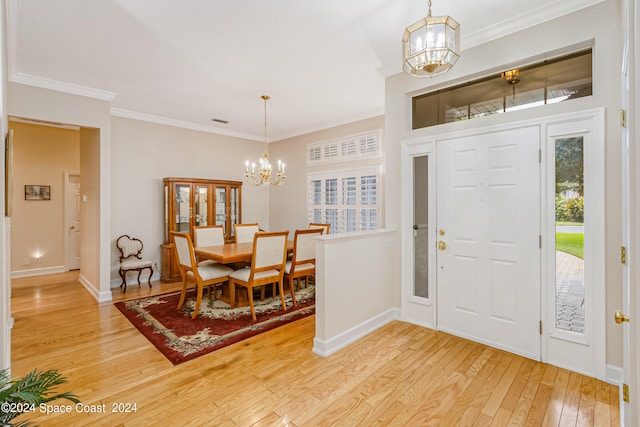 entryway featuring wood-type flooring, crown molding, and an inviting chandelier