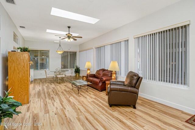 living room with wood-type flooring, a skylight, and ceiling fan