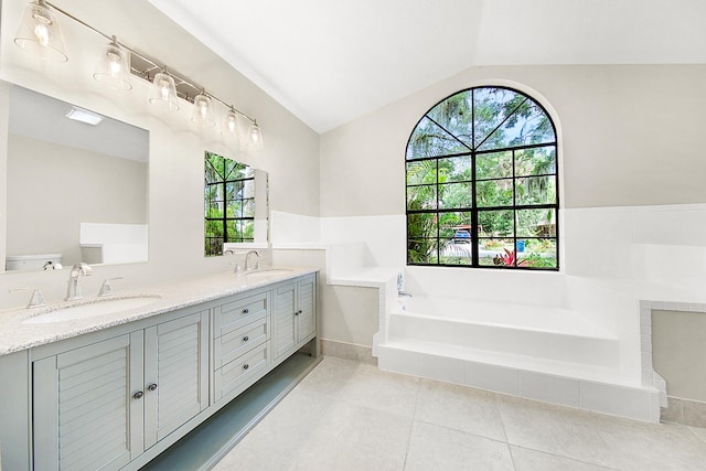 bathroom with tiled bath, vaulted ceiling, vanity, and a wealth of natural light