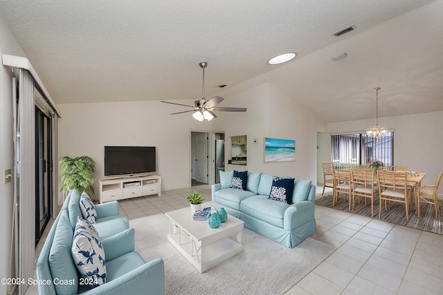 living room with lofted ceiling, ceiling fan with notable chandelier, a textured ceiling, and light tile patterned floors