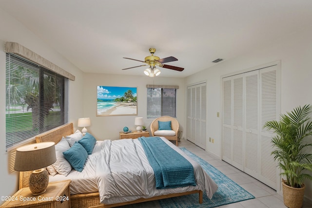 tiled bedroom with two closets and ceiling fan