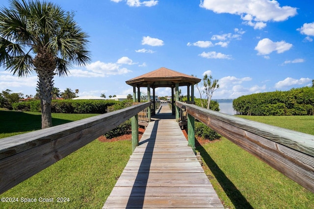 view of dock featuring a gazebo, a lawn, and a water view