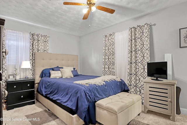 bedroom featuring a textured ceiling, ceiling fan, and light carpet