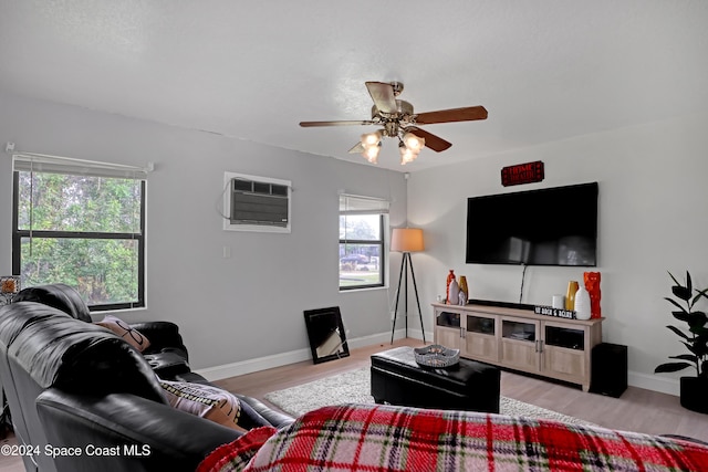 living room featuring a wall mounted air conditioner, ceiling fan, and light hardwood / wood-style flooring