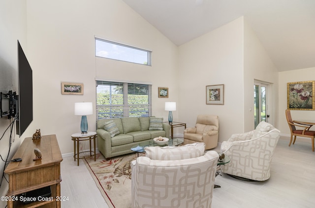 living room with high vaulted ceiling, light wood-type flooring, and a healthy amount of sunlight