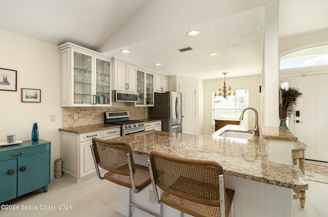 kitchen featuring sink, kitchen peninsula, white cabinetry, appliances with stainless steel finishes, and an inviting chandelier