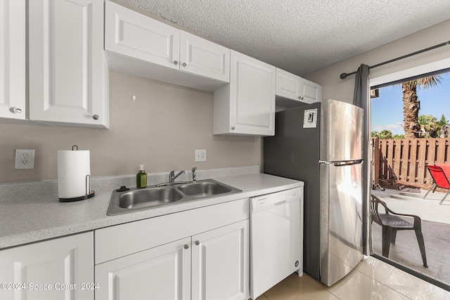 kitchen featuring a textured ceiling, light tile patterned flooring, sink, white cabinetry, and white dishwasher