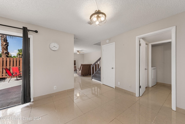 unfurnished room featuring ceiling fan, a textured ceiling, light tile patterned floors, and washer / dryer