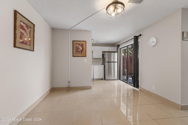 unfurnished room with a textured ceiling and light tile patterned flooring