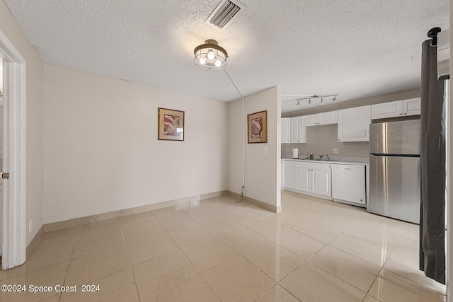 interior space with a textured ceiling, light tile patterned flooring, and sink