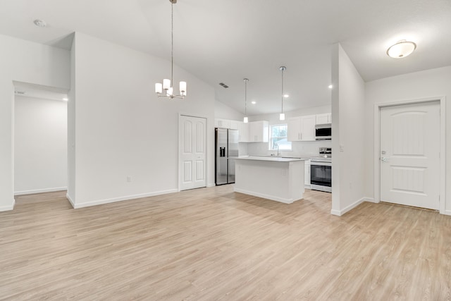 kitchen with light wood-type flooring, a center island, white cabinetry, appliances with stainless steel finishes, and decorative light fixtures