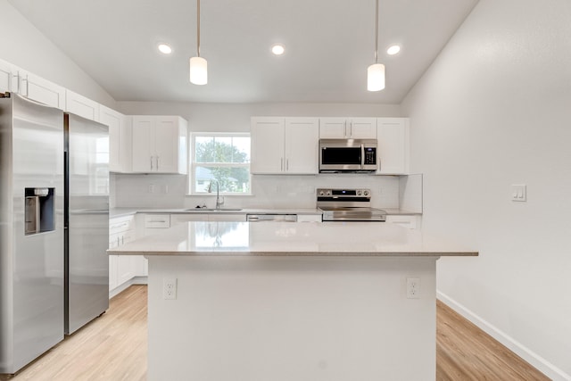 kitchen featuring decorative light fixtures, a center island, stainless steel appliances, and white cabinets