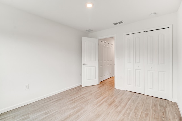 unfurnished bedroom featuring light hardwood / wood-style flooring and a closet