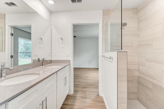 bathroom featuring hardwood / wood-style flooring, vanity, and tiled shower