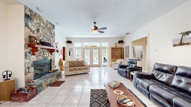 living room with light tile patterned flooring, a stone fireplace, ceiling fan, and french doors