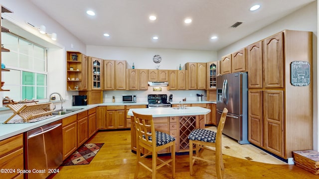 kitchen with appliances with stainless steel finishes, sink, a center island, and light hardwood / wood-style floors