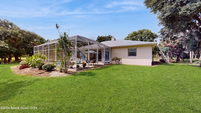 rear view of house with glass enclosure and a lawn