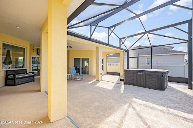 view of patio featuring ceiling fan, a lanai, and a hot tub