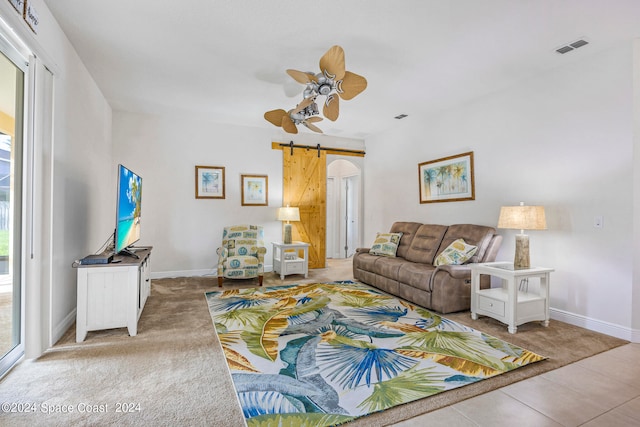 carpeted living room with a barn door and ceiling fan