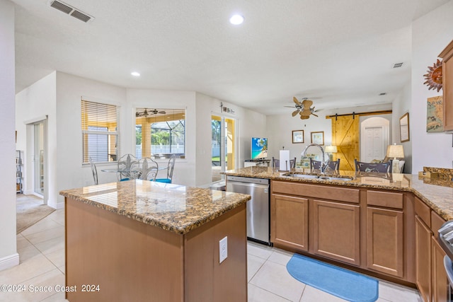 kitchen featuring sink, a kitchen island, a barn door, stainless steel appliances, and ceiling fan