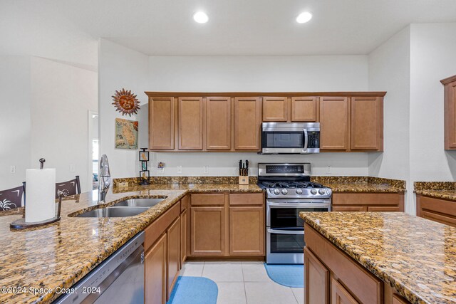 kitchen with light tile patterned floors, light stone countertops, stainless steel appliances, and sink