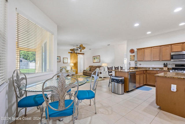 kitchen featuring kitchen peninsula, light stone countertops, light tile patterned floors, and stainless steel appliances