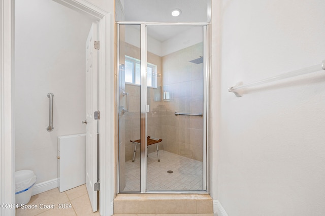 bathroom featuring toilet, tile patterned flooring, and a shower with door