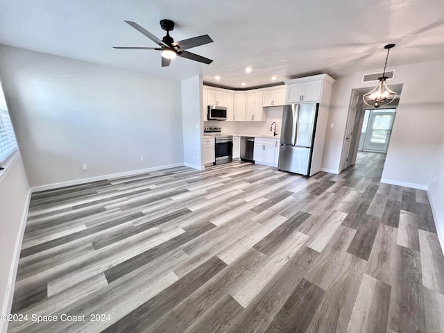 unfurnished living room with ceiling fan with notable chandelier, light wood-type flooring, and sink