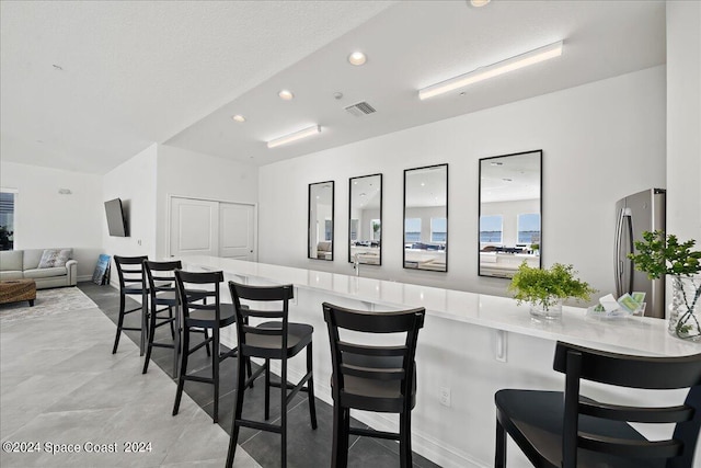 kitchen featuring stainless steel refrigerator, kitchen peninsula, and a breakfast bar area