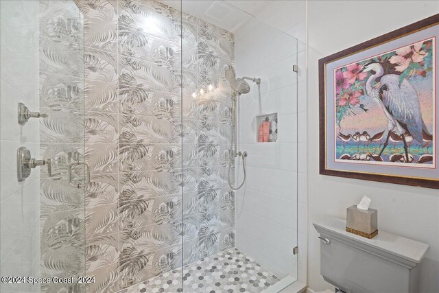 bathroom with a shower with door and toilet