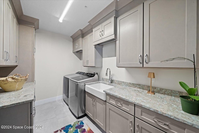 laundry room featuring cabinets, washer and clothes dryer, and sink