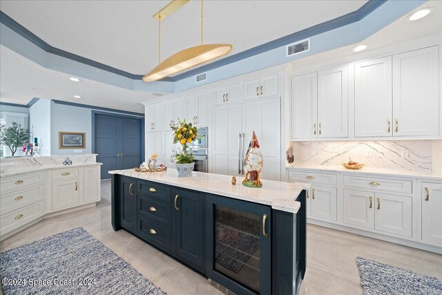 kitchen with white cabinets, beverage cooler, decorative light fixtures, and backsplash