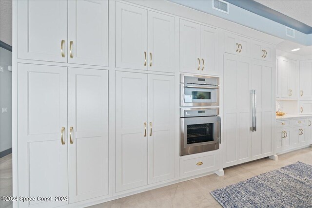 kitchen featuring dark stone countertops, double oven, and white cabinets