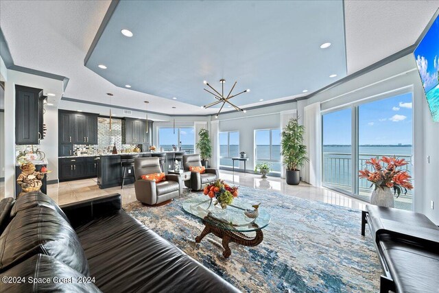 living room with a notable chandelier, light tile patterned floors, a healthy amount of sunlight, and crown molding