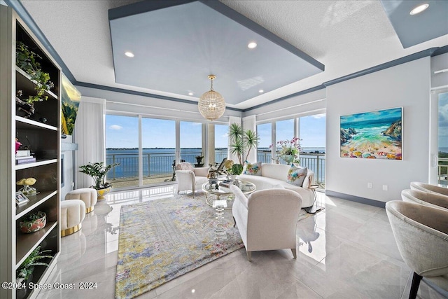 sunroom featuring a water view and a tray ceiling