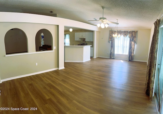 unfurnished living room featuring vaulted ceiling, ceiling fan, dark wood-type flooring, and a textured ceiling