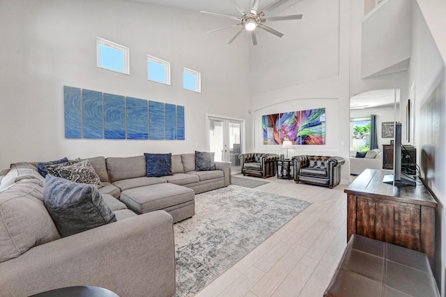 living room featuring a high ceiling, light hardwood / wood-style flooring, and plenty of natural light