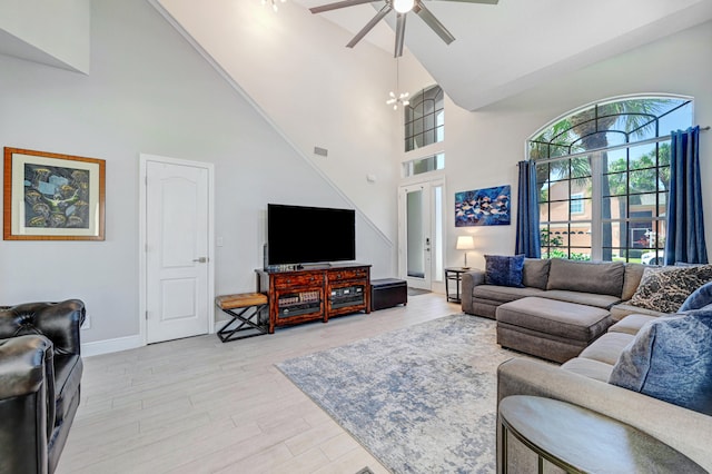 living room with ceiling fan with notable chandelier, light hardwood / wood-style flooring, and high vaulted ceiling