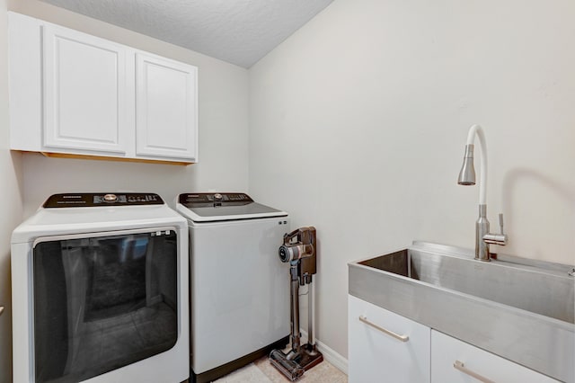 laundry room featuring a textured ceiling, cabinets, sink, and independent washer and dryer