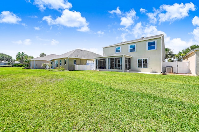 back of property with a lawn, a sunroom, and central AC