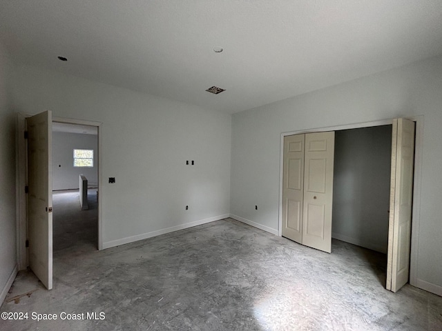 unfurnished bedroom with concrete floors and a closet