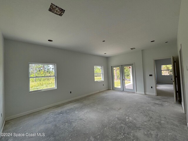 empty room featuring a textured ceiling and french doors