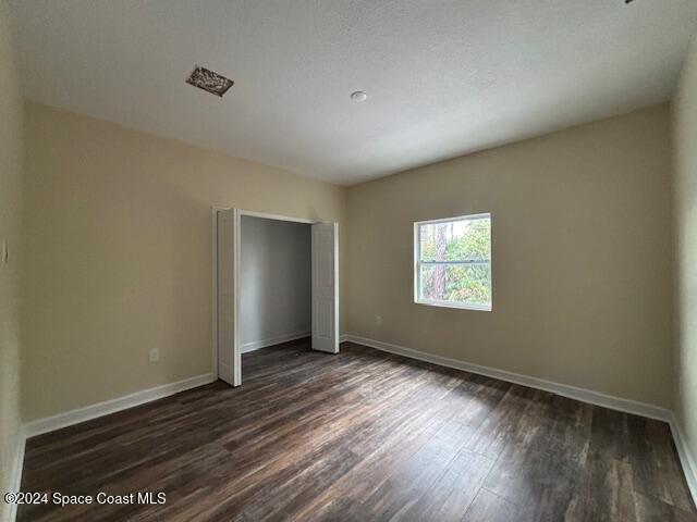 unfurnished bedroom with a textured ceiling and dark wood-type flooring